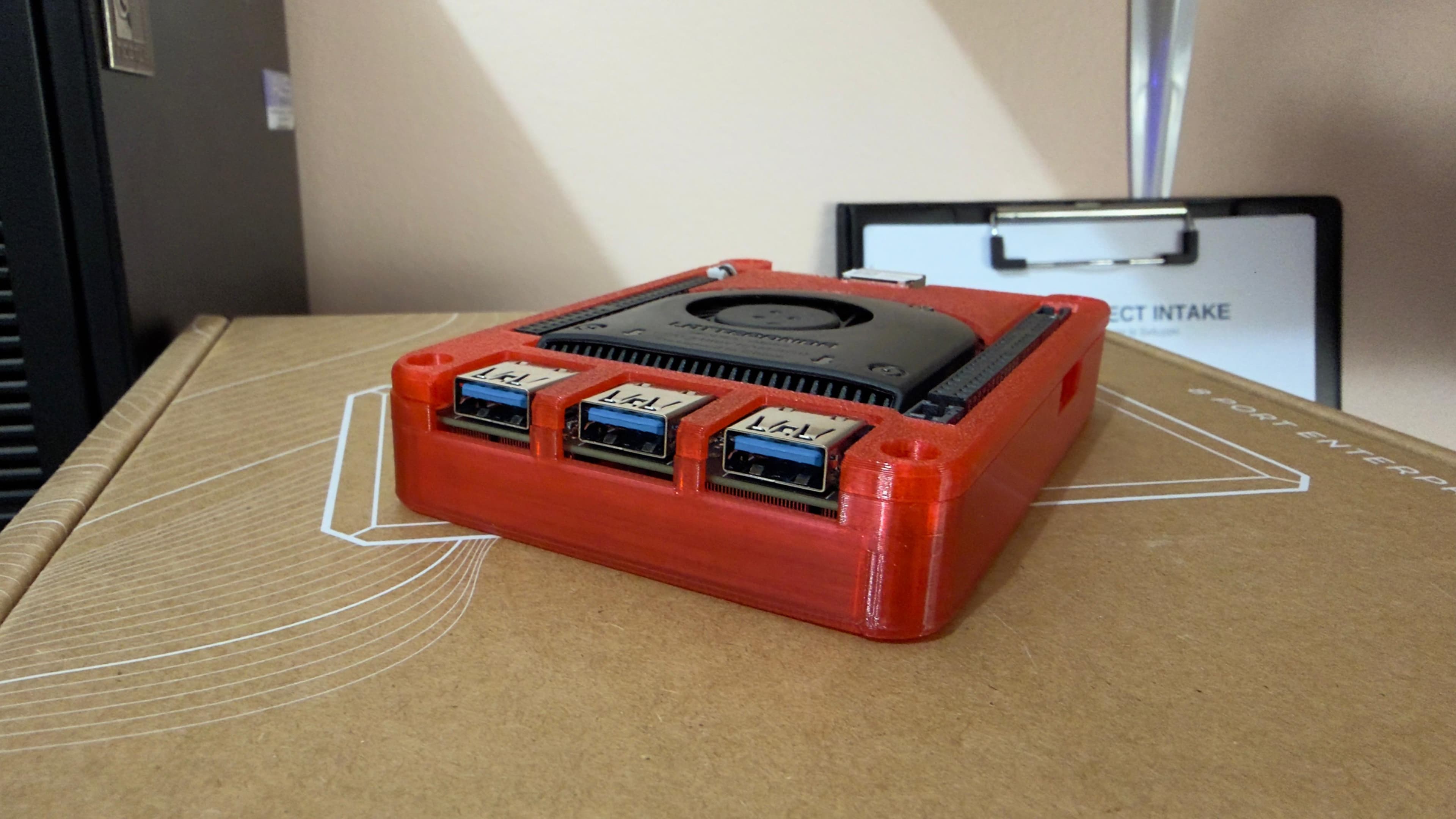 LattePanda Alpha in case stampato in 3D con filamento PLA rosso SUNLU, poggiata sulla scatola di uno switch MokerLink — tre porte USB 3.0 visibili