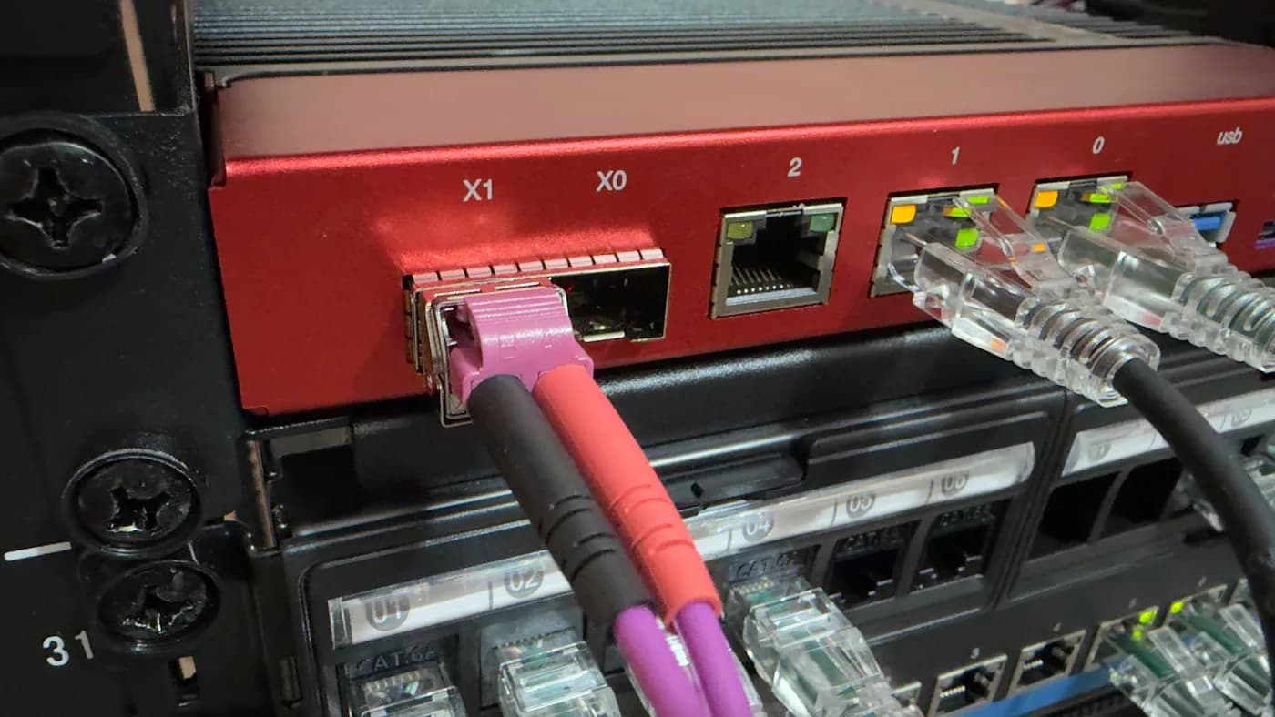 Dettaglio delle porte del firewall Deciso DEC750 con un transceiver SFP+ e una fibra LC magenta collegata sulla porta X1