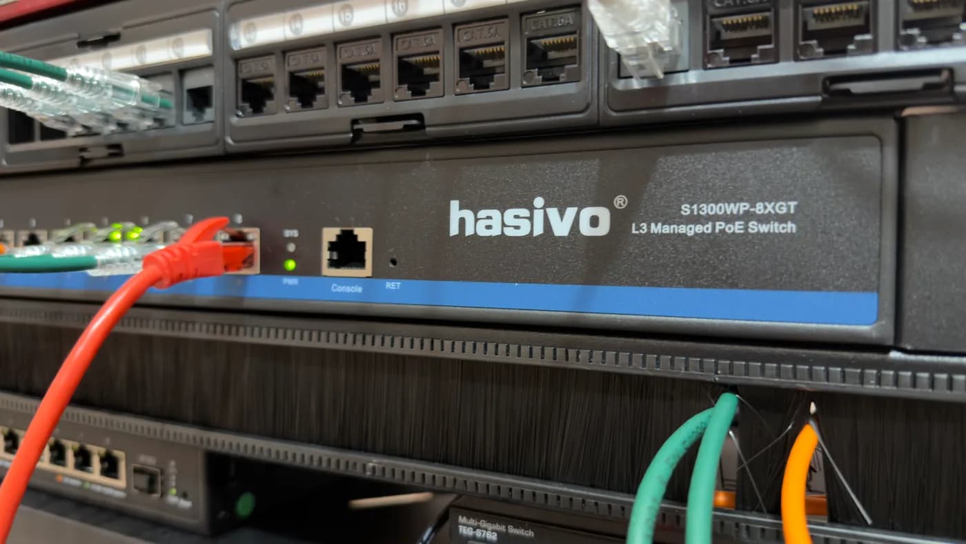 Primo piano dello switch Hasivo S1300WP-8XGT con la scritta L3 Managed PoE Switch, una patch arancione e una verde collegate